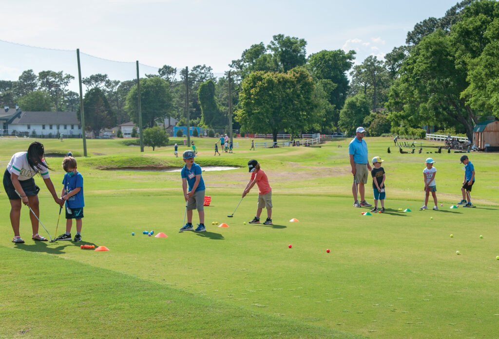 Keyona Williams, outreach and program coordinator, and Craig Sandstrum, director of programming, introduce children ages 5 and 6 to the game of golf through First Tee’s Little Linksters class. Photo by Allison Potter