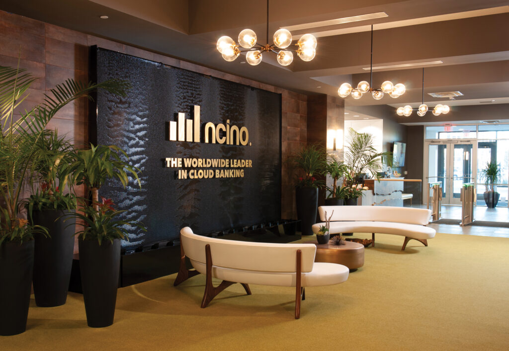 The entrance lobby to the global corporate headquarters of nCino features a statement-making water wall, vintage light fixtures and lush green botanicals. Photo by Allison Potter