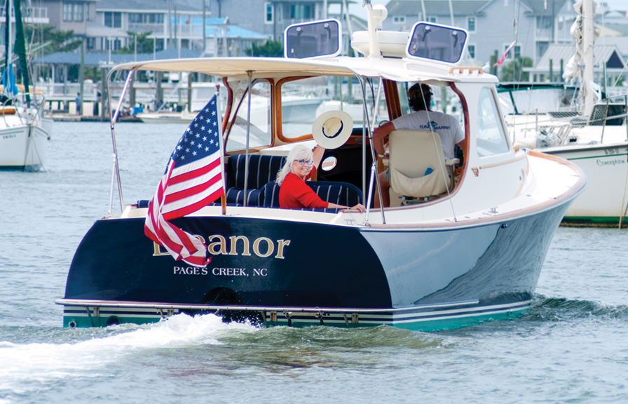 Pat Bradford aboard Eleanor, Simon Robson’s classic wooden Hinckley (Cape Fear Hinckley Club) in Banks Channel on Flag Day 2022. Pat’s Hair by Frank Potter, styled by Mason Chandler, makeup by Regan Daughtry.  All from Bangz Hair Salon.  Photo by Allison Potter
