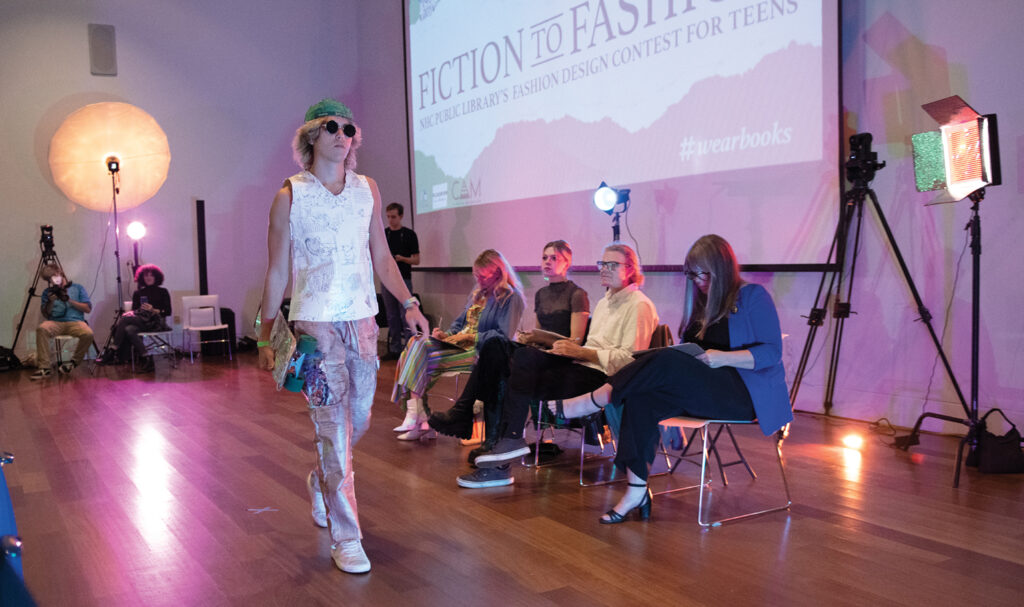 Upscale, designed by Maggie Carter and modeled by Noah Carter. The shirt and pants are made of book pages, the hat is book bindings, and the skateboard is decorated with broken CDs for a thrasher look. Photo by Allison Potter